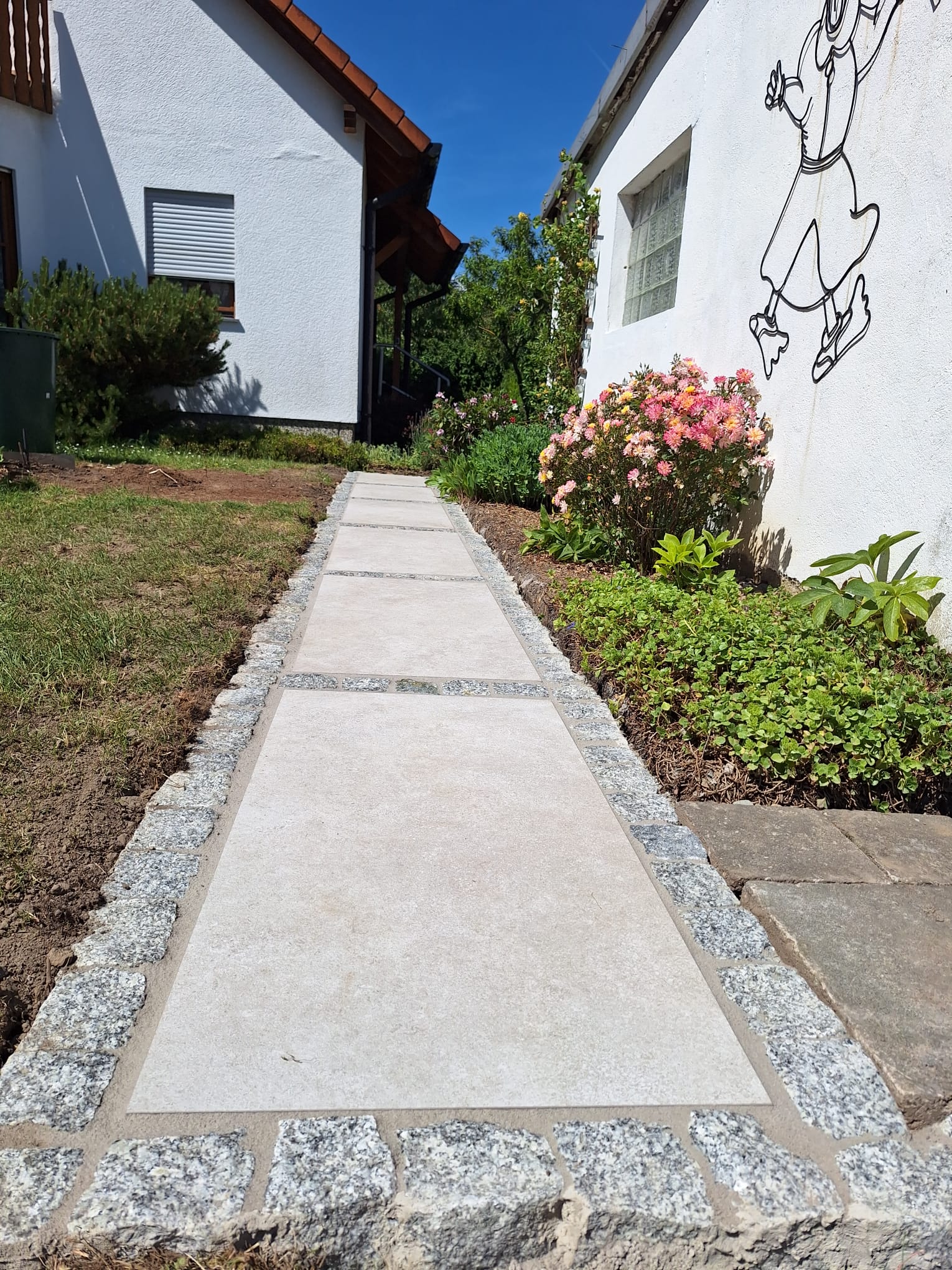 Neu verlegter Plattenweg mit Granit-Bordüre und Blumenbeet